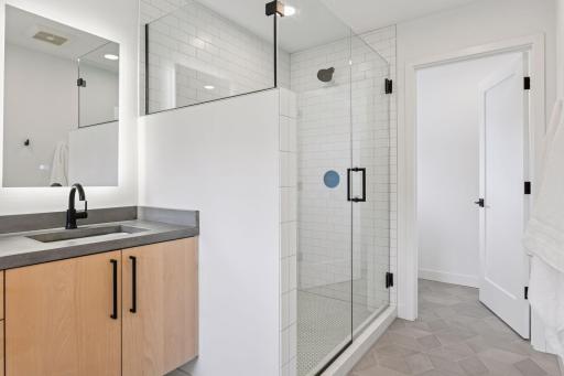 The custom cabinetry is stunning and the floor to ceiling tile shower with a glass enclosure beautifully designed
