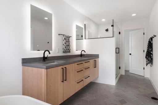 A gorgeous double sink with custom mirrors, honed concrete counters, gorgeous hardware and heated floors