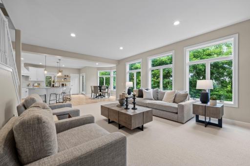 Expansive windows flood the room with natural light, while 9-foot ceilings and an open-concept layout create a spacious, airy feel that flows seamlessly into the adjacent kitchen and dining areas.