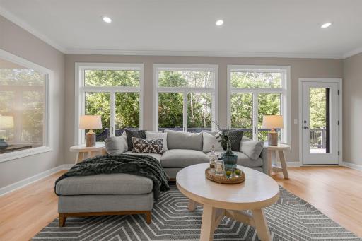 The sunroom has expansive windows that flood the room with natural light, while 9-foot ceilings and an open-concept layout create a spacious, airy feel that flows seamlessly into the adjacent kitchen and dining areas.