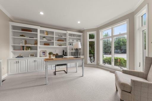The main-level office, perfect for working from home, features a large front-facing bay window, French doors, brand new carpeting, recessed lighting, and built-in shelving and cabinetry.