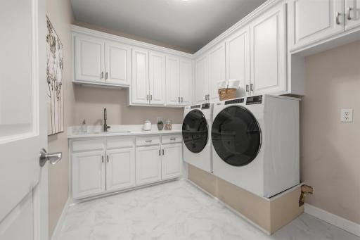 The laundry room featuring sleek new front-loading Whirlpool washer and dryer units, quartz countertops, built-in cabinetry, and a sinkâmaking daily chores both efficient and stylish.