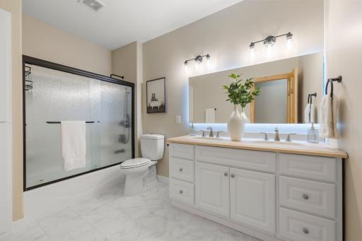 Just steps away from both bedrooms is a beautifully updated full bathroom with tile flooring, a double vanity, and a built-in linen cabinet.