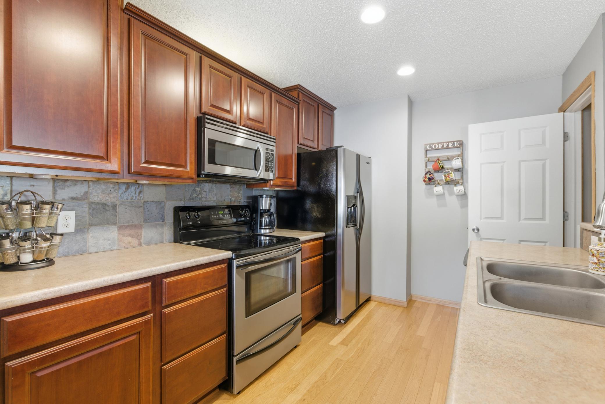Beautiful kitchen with cherry stained cabinets, slate backsplash, and stainless steel appliances.
