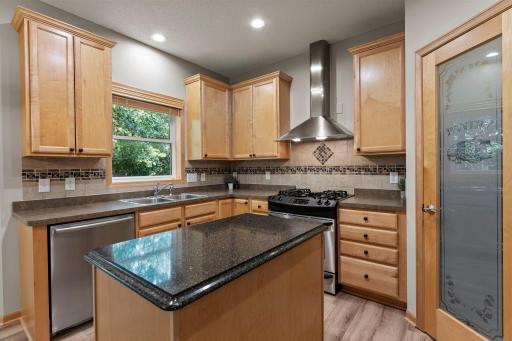 The kitchen includes a tile backsplash and granite countertop on the island.