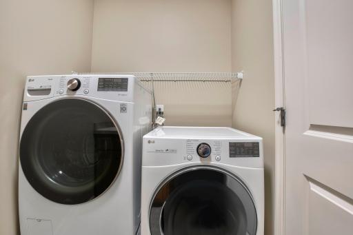 Front-load LG washer and dryer set with upper wire shelving in dedicated laundry room.