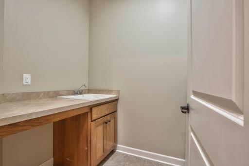 Dedicated laundry room with utility sink, folding counter, and wood cabinetryâideal for chores and storage.