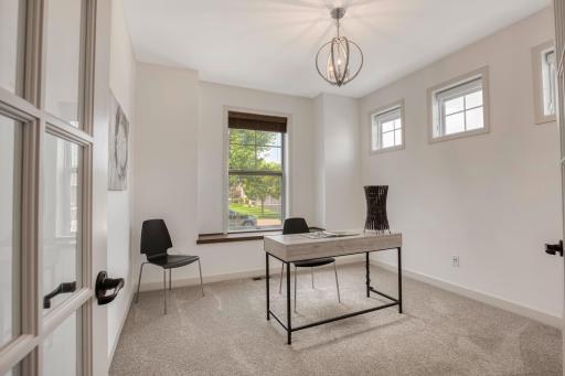 Bright and versatile front room features plush carpet, modern lighting, and charming windows for natural lightâperfect for a home office or guest room.