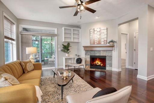 Expansive walk-out main level room with gleaming wood floors and a cozy fireplace.