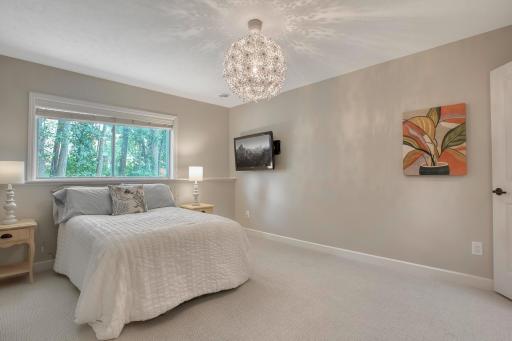 Lower-level bedroom with large window, TV mount, and unique modern light fixture.