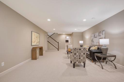 Expansive finished lower-level family room with neutral carpet and recessed lighting.