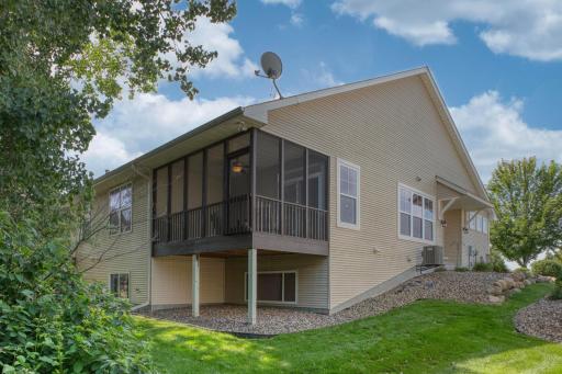 Attractive back view featuring a screened-in porch and landscaped yard with rock edging.