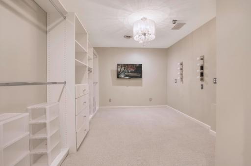 Stunning custom dressing room with built-in shelving, drawers, and vanity lighting setup.