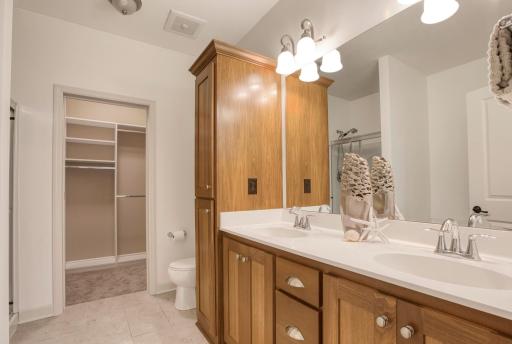 Elegant en suite bathroom with dual sinks, custom cabinetry, and direct access to the walk-in closet.