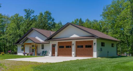 This custom-built patio home, completed in 2022, is situated on eight wooded acres with approximately 300 feet of lakefront. The sandy bottom offers a private swimming area, and state land borders the property on the south side