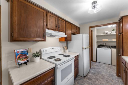 The adjacent galley kitchen blends function with timeless appeal. Outfitted with classic wood cabinetry, a large closet pantry, and an updated electric range with hood vent, itâs designed to make cooking both simple and enjoyable.