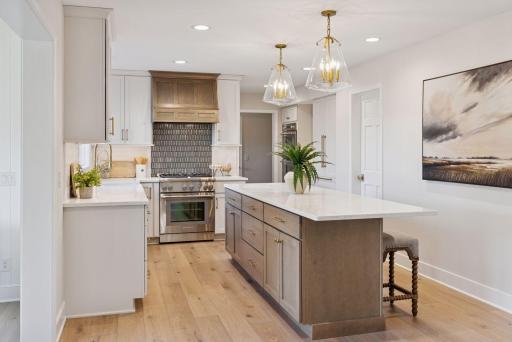 Kitchen oasis featuring a brand-new kitchen window that floods the space with natural light, elegant island pendants, and a striking glass tile backsplash behind the range.