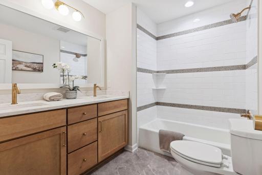 Explore the renovated upper-level bathroom, featuring new flooring, countertops, vanity, shower tile, and modern light fixtures for a fresh look