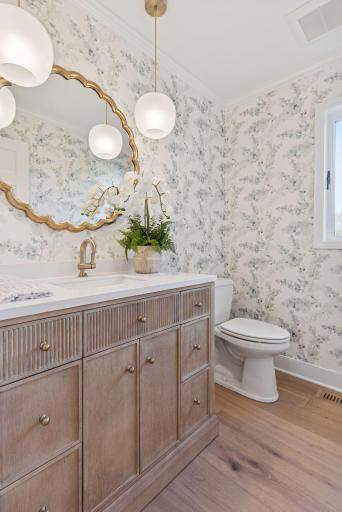Step into the fabulous and updated main floor powder bathroom, featuring a stylish reeded vanity and beautifully detailed wallpaper.