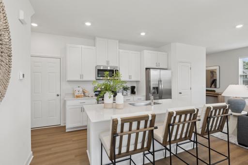 (Photo is of a model home, finishes will vary) A multifunctional center island pairs with abundant cabinetry and all-new stainless steel appliances to create a sleek design in this breezy kitchen—perfect for cooking meals of all sizes.