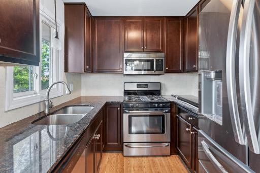 Galley Kitchen has granite countertop, stainless steel appliances and kitchen window.