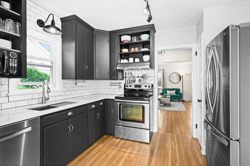 Updated kitchen with quartz countertops, a large stainless steel sink and painted cabinetry.
