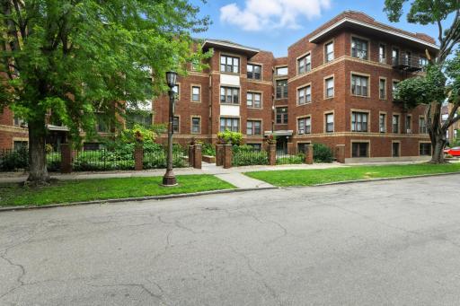 Classic brick building with timeless architectural details, mature trees, and well-kept landscaping creating a charming curb appeal.