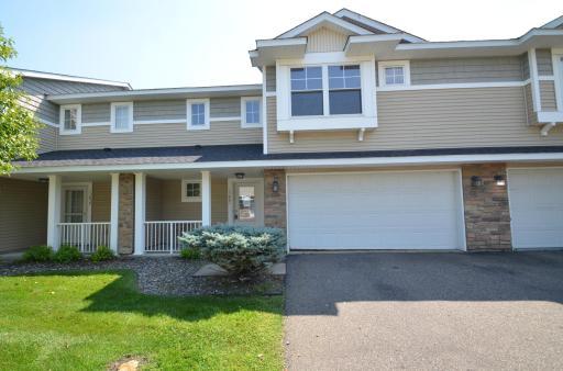 Beautiful townhome in Plymouth with stone accents, covered porch, and a two-car garage and well-maintained landscaping.