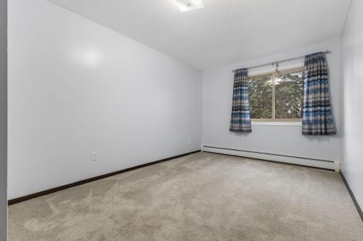 The second bedroom boasts plush carpeting, neutral paint, and natural light. It is convenient to the primary bedroom ideal for keeping loved ones close.
