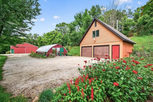View of the green house and 4 stall detached garage with bonus space above.