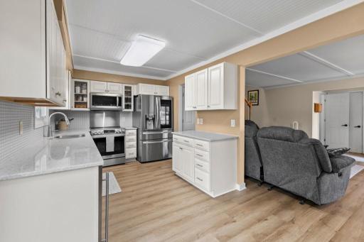 Completely updated kitchen featuring sleek stainless steel appliances, quartz countertops, and crisp white cabinetry. The open design flows seamlessly into the living area, highlighted by modern flooring, fresh finishes, and ample storage.
