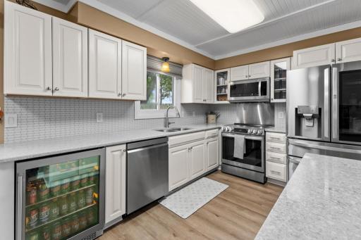 This updated kitchen features quartz countertops, stainless steel appliances, and a sleek beverage fridge for added convenience. Bright cabinetry and modern finishes create a stylish and functional space.