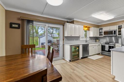 Bright and functional kitchen with quartz counters, stainless steel appliances, and a beverage fridge, opening to a newer sliding glass door that leads out to your deck and storage shedâperfect for indoor-outdoor living.