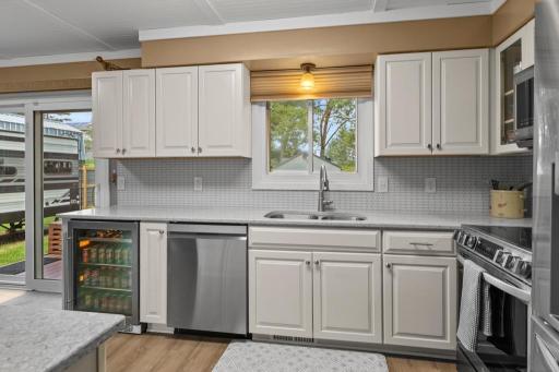 This updated kitchen features quartz countertops, stainless steel appliances, and a sleek beverage fridge for added convenience. Bright cabinetry and modern finishes create a stylish and functional space.