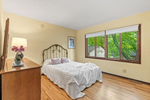 Primary bedroom features wood floors and large sun-filled windows.
