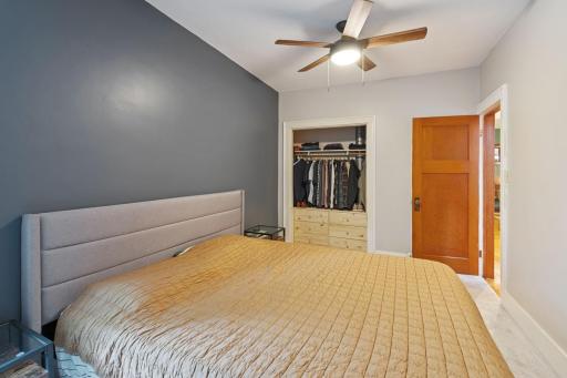 Another view of the main floor primary bedroom with ceiling fan, and a second spacious closet with built-in storage.