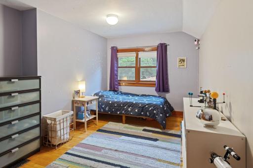 Upper-level bedroom with hardwood floors, a large window for natural light, and a spacious layout.