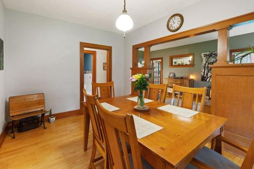 Charming dining room showcasing rich wood trim, hardwood floors and built-in architectural details. Open layout connects seamlessly to the living room, creating a comfortable and welcoming space.