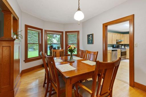 Bright and inviting dining room features a charming bay of windows overlooking the yard. The space flows seamlessly into the kitchen, creating a perfect setting for meals and entertaining.