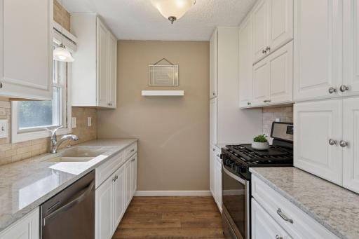 Crisp white cabinets are paired with granite countertops, a double sink, and stainless steel appliancesâincluding a gas range.