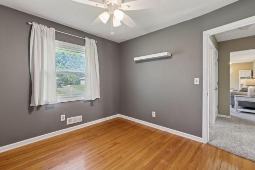 Bedroom 3 with original hardwood floors, ceiling fan, white trim.