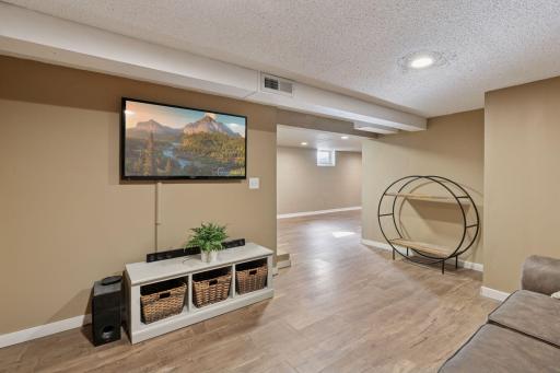 This level includes a cozy media area perfect for movie nights, along with a larger open space designed for entertaining or recreation.