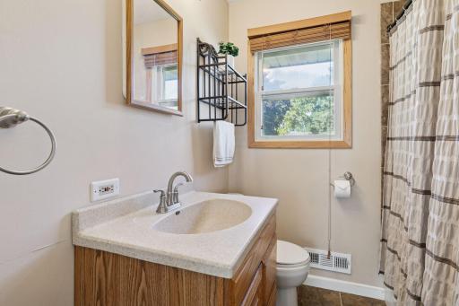 Main floor full bath with tiled floors, updated vanity, sink, and decor.