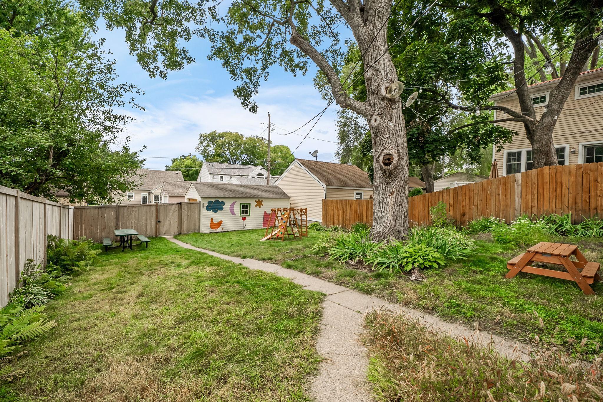 Spacious lot with a newer privacy fence, single stall garage, and additional concrete parking pad/driveway.