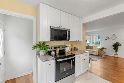 Fully renovated kitchen featuring brand-new cabinets, countertops, range, and microwave.