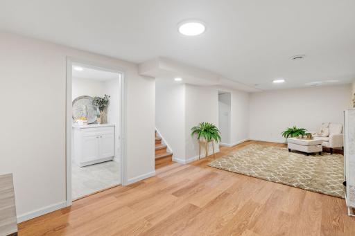 Finished basement with new flooring, modern lighting, and convenient access to an additional bedroom and bathroom.