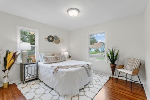 Bedroom features hardwood flooring and ample natural light from the windows.
