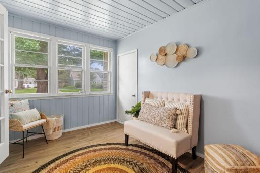 Bright sitting room featuring updated flooring, windows, and convenient access to the garage.