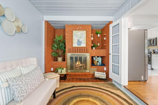 Cozy sitting room with a charming brick fireplace and new flooring.