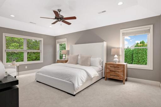 Huge primary bedroom suite has a tray vault ceiling and large windows